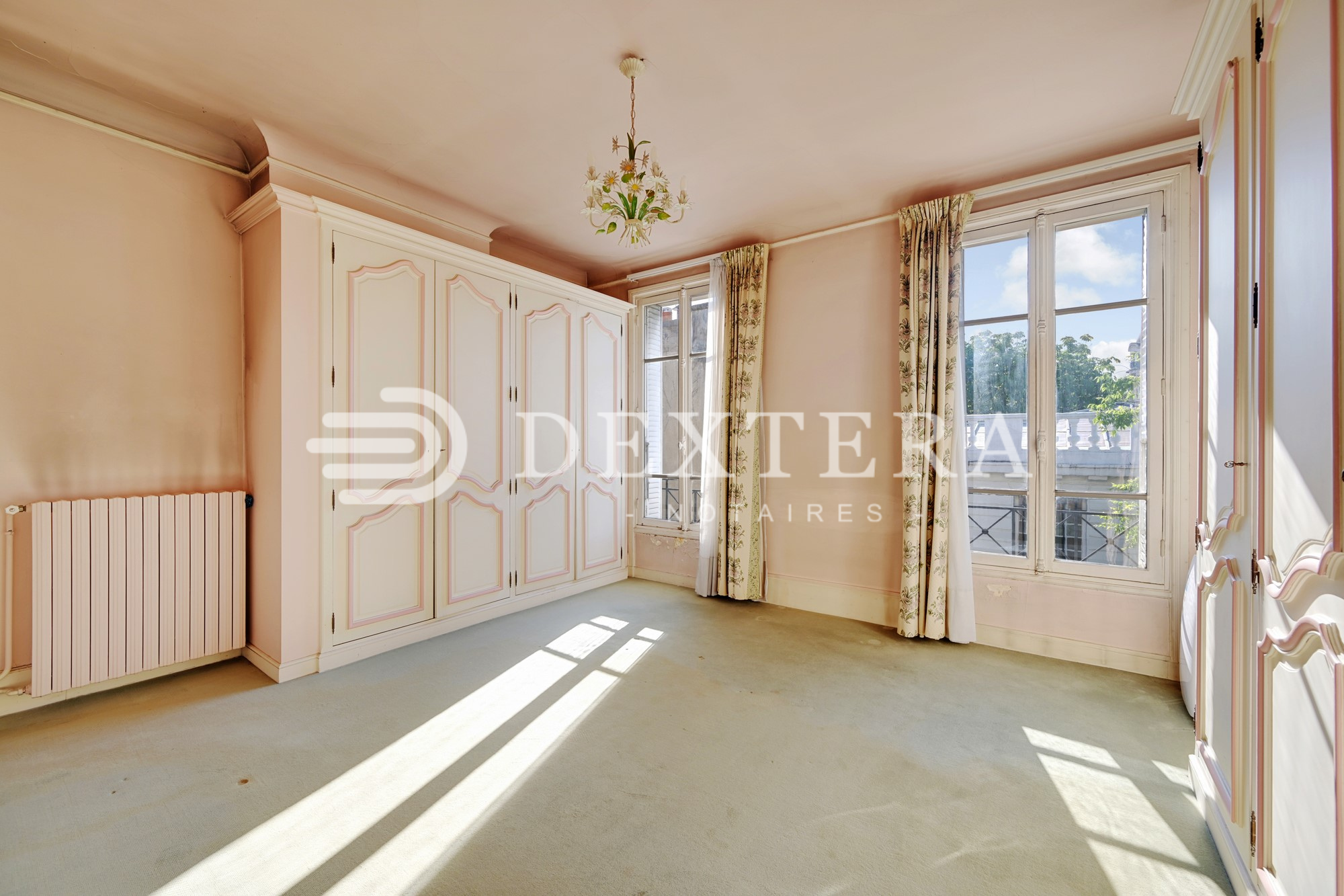 Hôtel Particulier à Neuilly-sur-Seine : Chambre lumineuse avec placards intégrés, moquette claire et vue arborée.