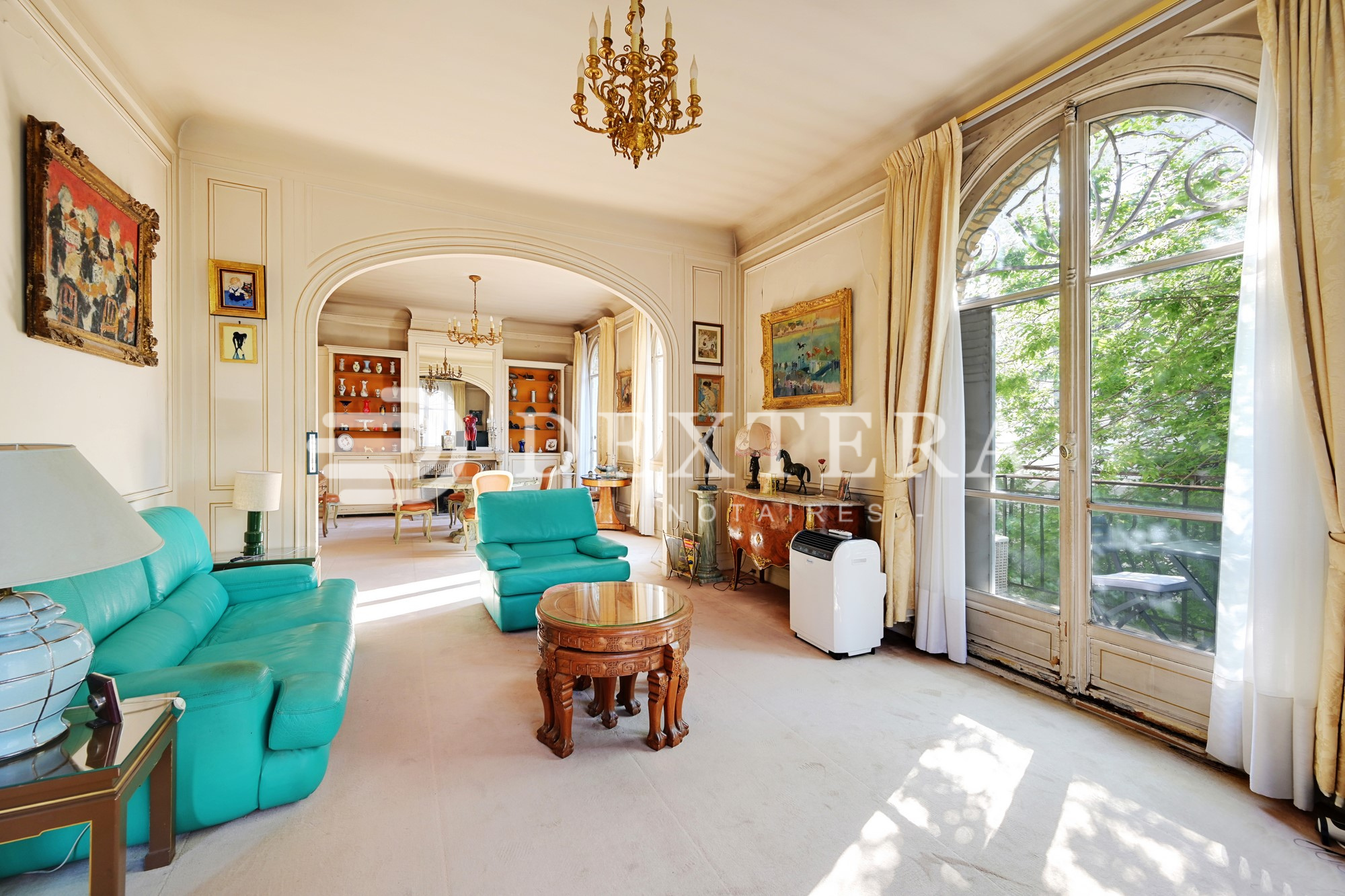 Hôtel Particulier à Neuilly-sur-Seine : Double séjour lumineux avec grandes fenêtres cintrées et parquet point de Hongrie dans un hôtel particulier à Neuilly-sur-Seine.