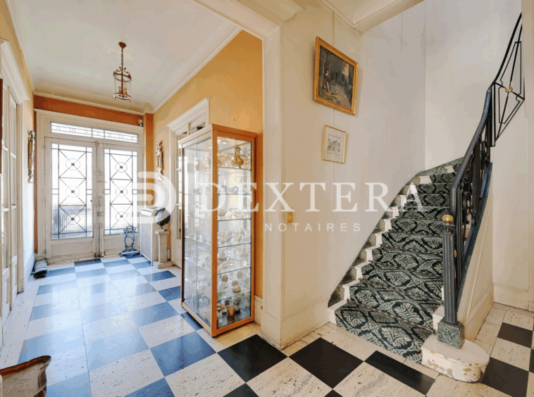 Hôtel Particulier à Neuilly-sur-Seine : Hall d’entrée avec sol en damier noir et blanc et escalier ancien dans un hôtel particulier à Neuilly-sur-Seine.