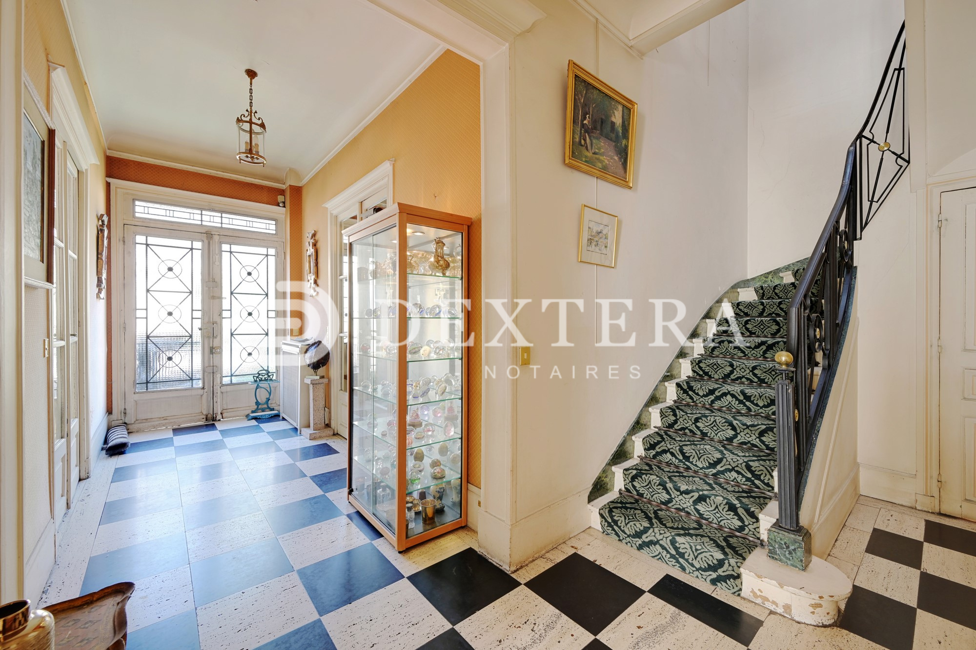 Hôtel Particulier à Neuilly-sur-Seine : Hall d’entrée avec sol en damier noir et blanc et escalier ancien dans un hôtel particulier à Neuilly-sur-Seine.