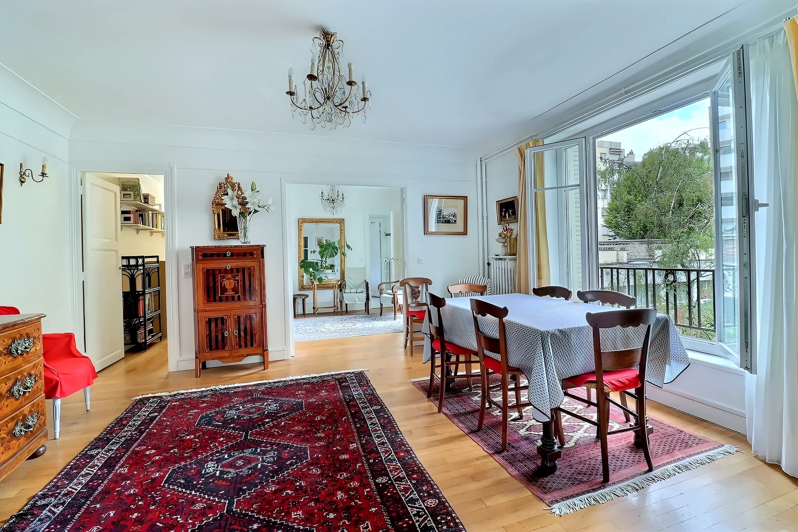 Salon avec parquet, miroir ancien et fenêtre ouverte sur les jardins du square Charles Laurent à Paris 15e