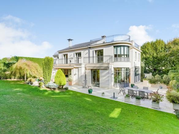 Façade de la maison à Ville-d'Avray avec terrasse en pierre, grandes baies vitrées et jardin paysager.
